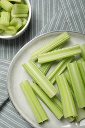Photo of Fresh green cut celery on striped tablecloth, flat lay