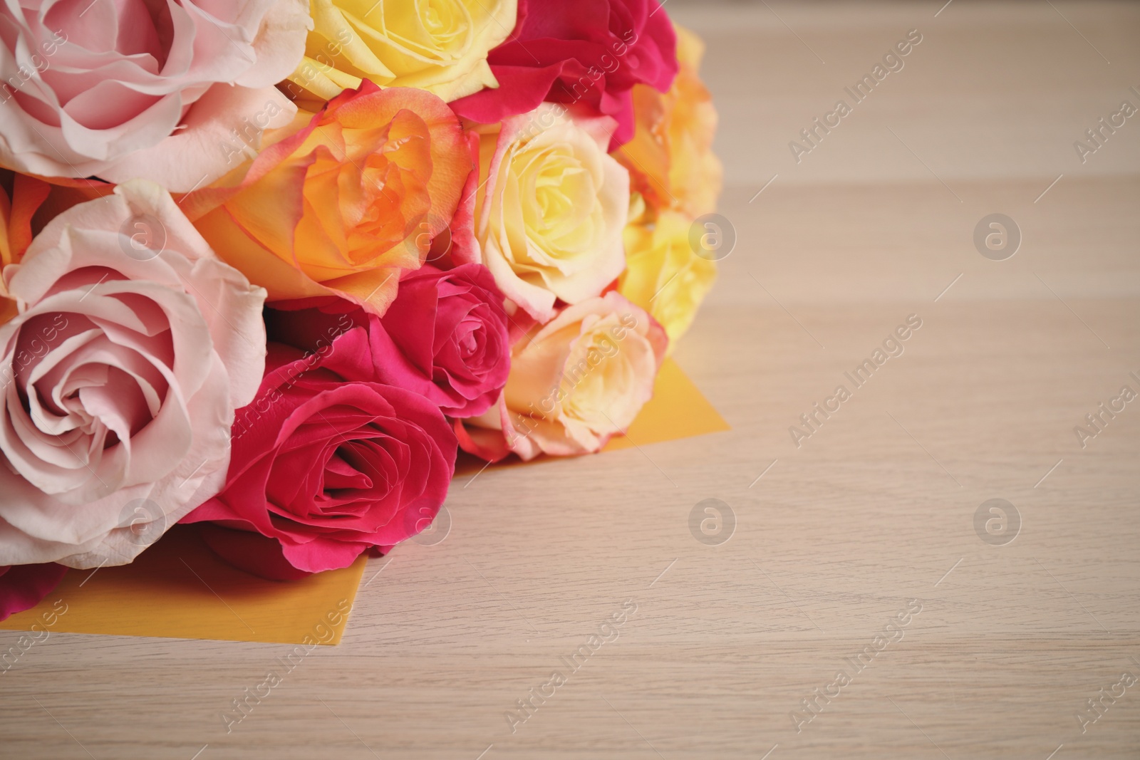 Photo of Luxury bouquet of fresh roses on wooden table, closeup. Space for text