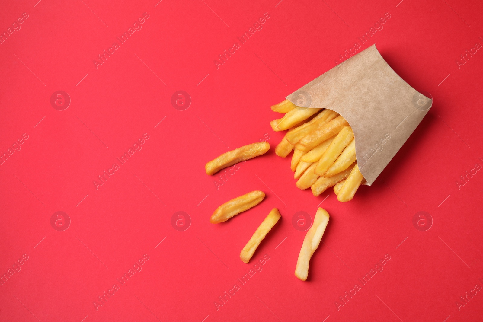 Photo of Paper cup with French fries on red table, flat lay. Space for text