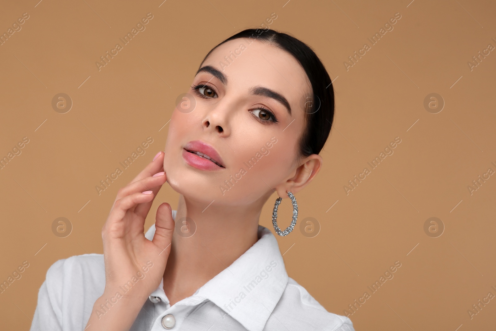 Photo of Beautiful young woman with elegant earrings on beige background