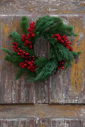 Photo of Beautiful Christmas wreath with red berries hanging on wooden wall