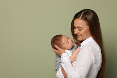 Photo of Mother holding her cute newborn baby on olive background, space for text