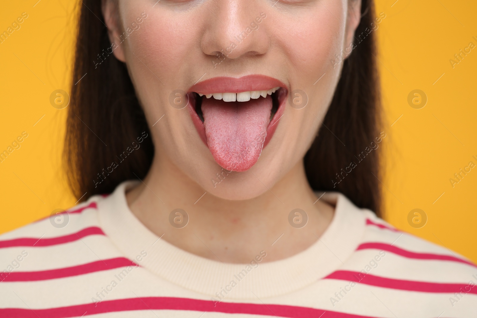 Photo of Woman showing her tongue on orange background, closeup