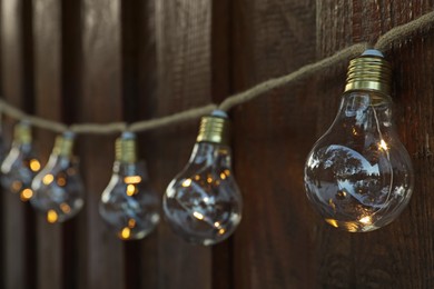 Photo of Garland of lamp bulbs hanging on wooden wall. String lights