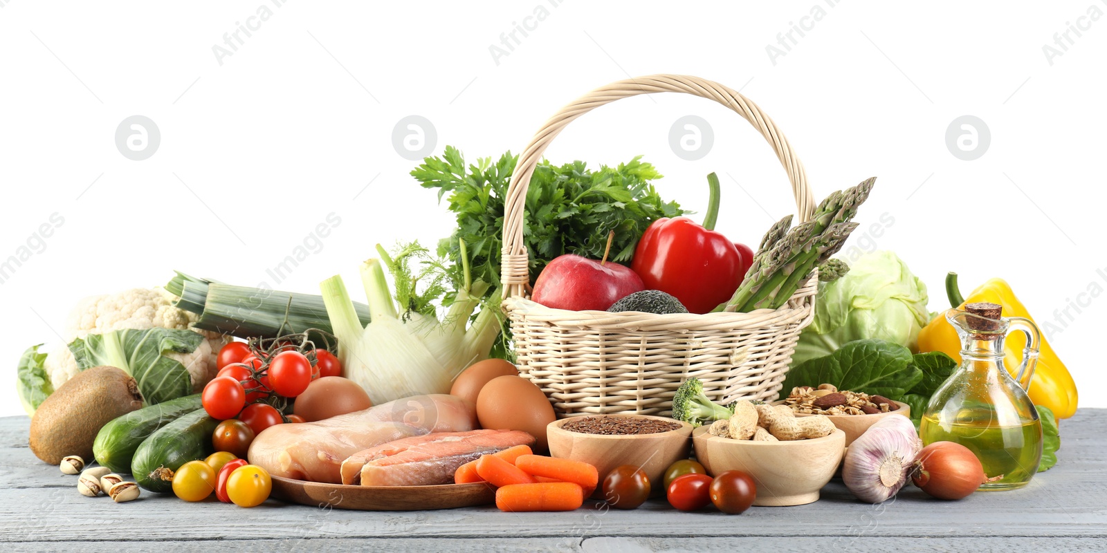 Photo of Healthy food. Basket with different fresh products on grey wooden table against white background