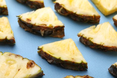 Photo of Pieces of tasty ripe pineapple on light blue background, closeup