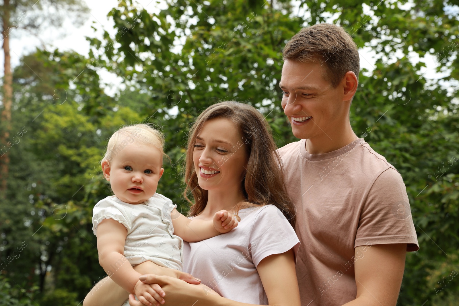 Photo of Parents with their cute baby spending time together outdoors. Happy family