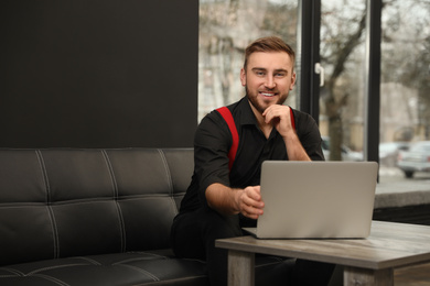 Photo of Young business owner with laptop on couch indoors