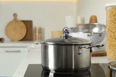 Shiny pot on electric stove in kitchen. Cooking utensil