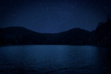 Image of Amazing starry sky reflecting in lake. Beautiful night landscape