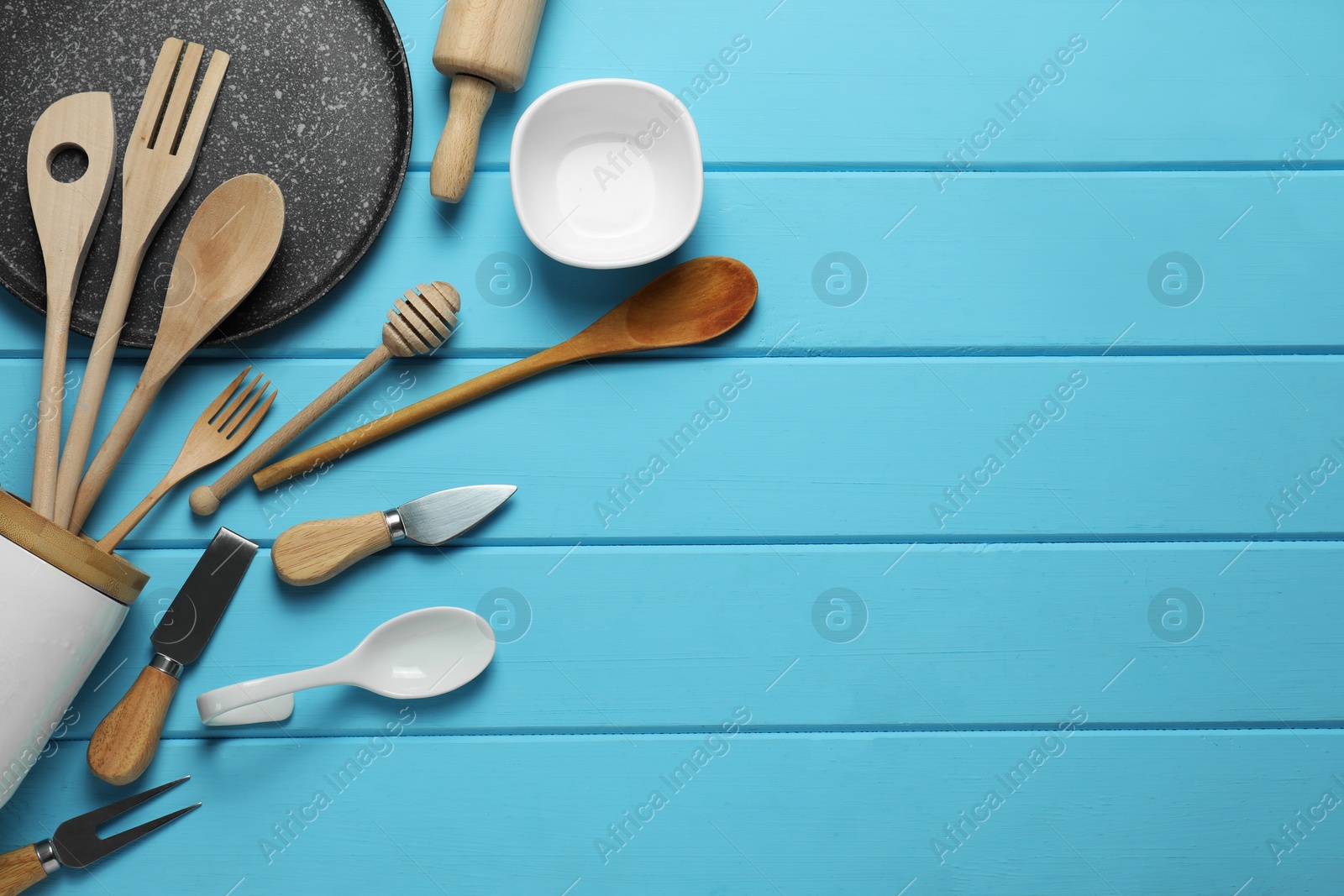 Photo of Set of different kitchen utensils on light blue wooden table, flat lay. Space for text