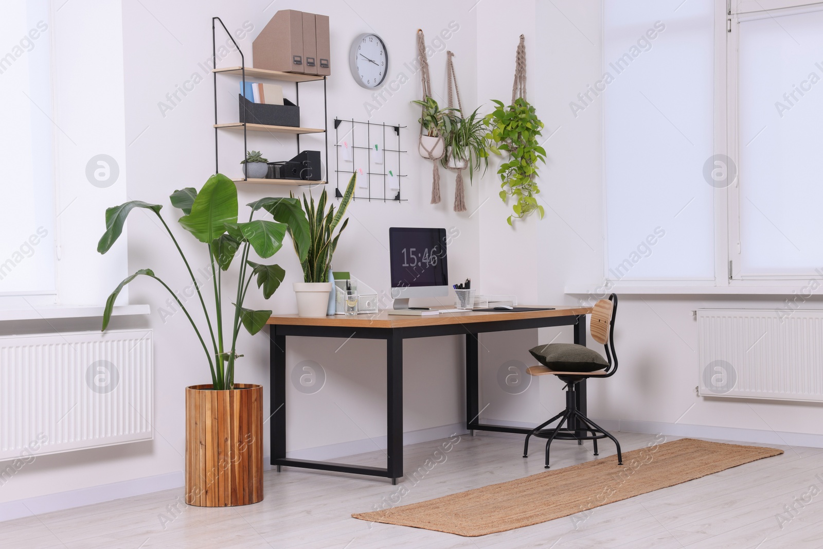 Photo of Cozy workplace with computer, modern furniture and houseplants at home