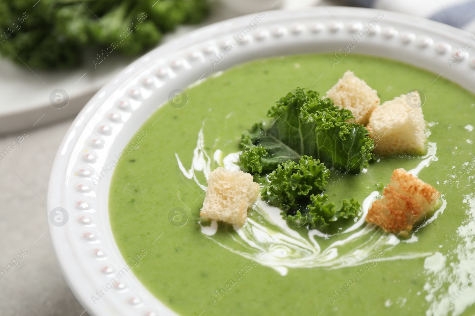 Photo of Tasty kale soup with croutons on table, closeup