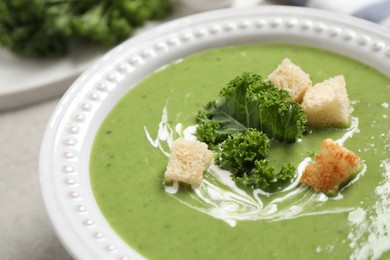 Tasty kale soup with croutons on table, closeup