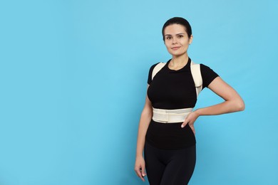 Photo of Beautiful woman with orthopedic corset on blue background, space for text