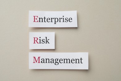 Photo of Cards with abbreviation ERM (Enterprise Risk Management) on beige background, flat lay