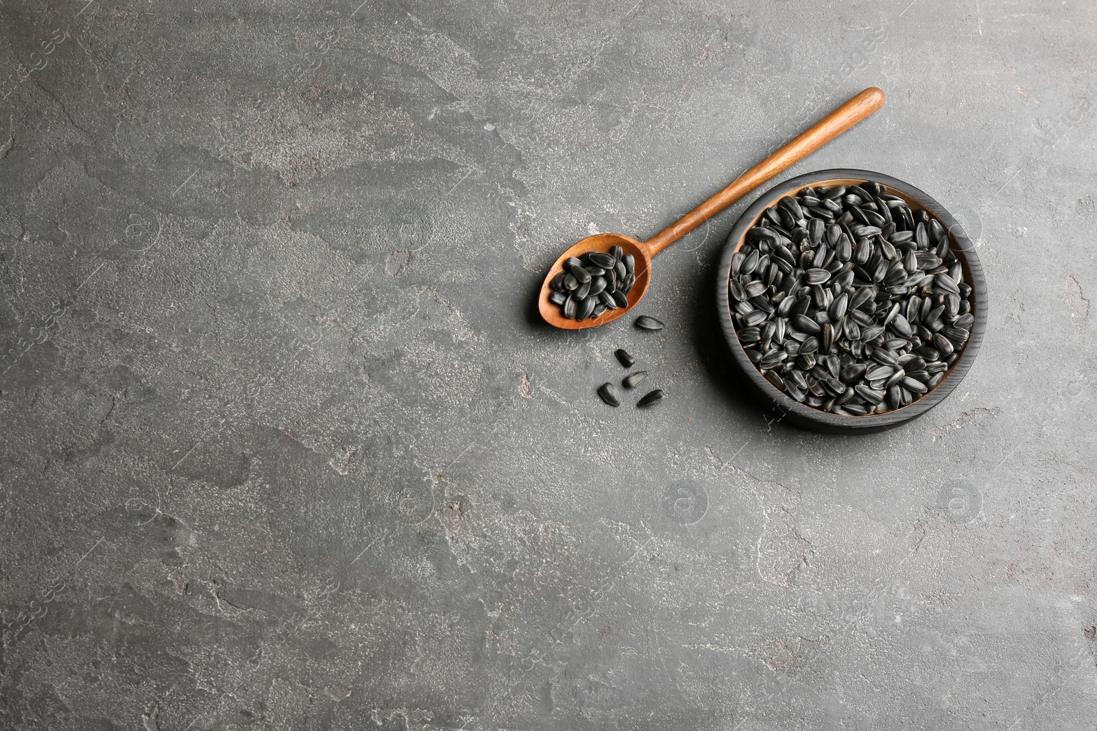 Photo of Bowl and spoon with sunflower seeds on table, top view