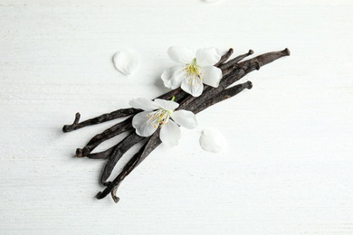 Photo of Aromatic vanilla sticks and flowers on wooden background