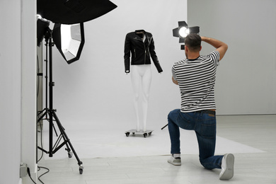 Professional photographer taking picture of ghost mannequin with stylish clothes in modern photo 
 studio