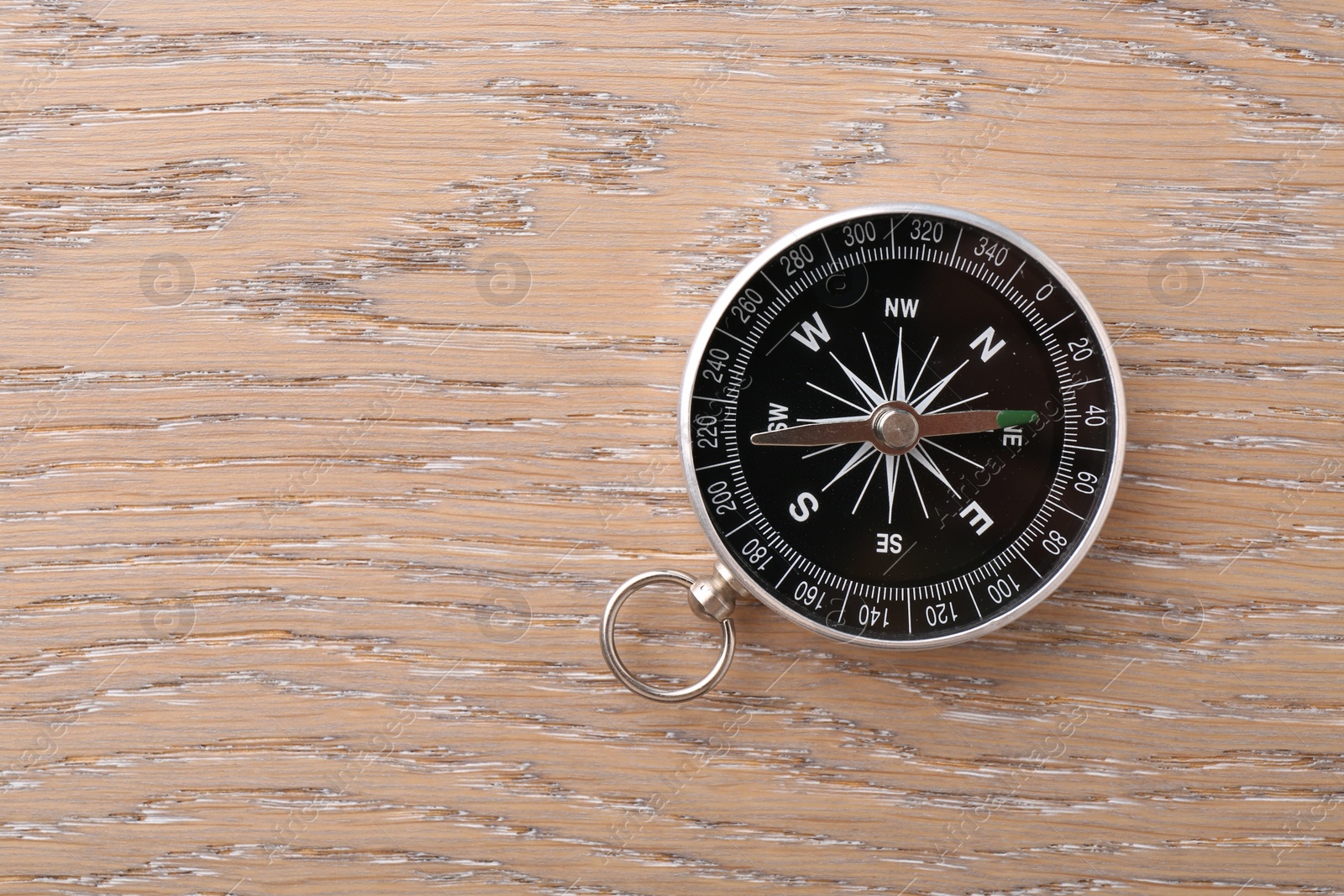 Photo of One compass on wooden table, top view. Space for text