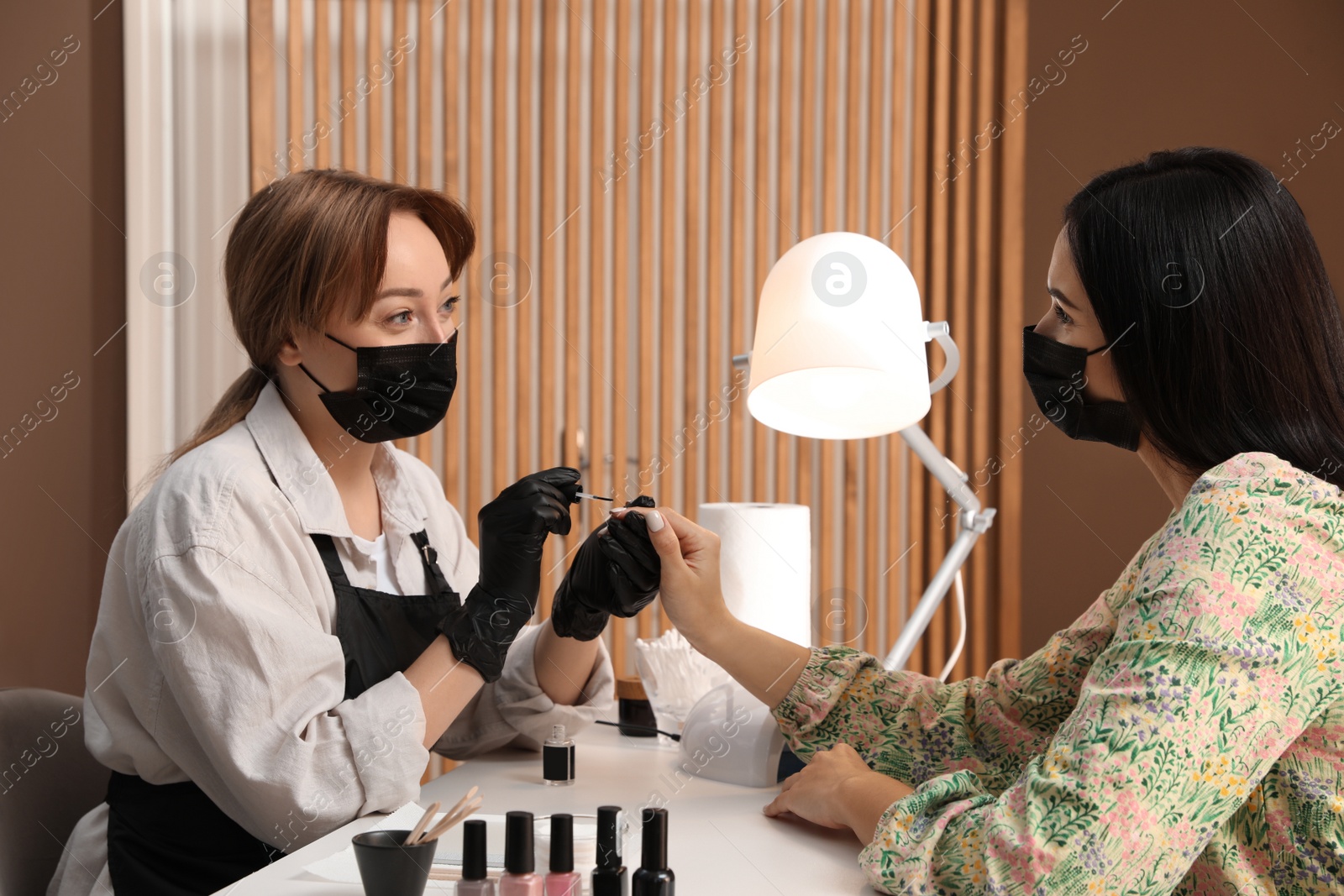 Photo of Professional manicurist working with client in salon. Beauty services during Coronavirus quarantine