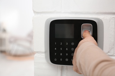 Photo of Man scanning fingerprint on alarm system at home, closeup. Space for text