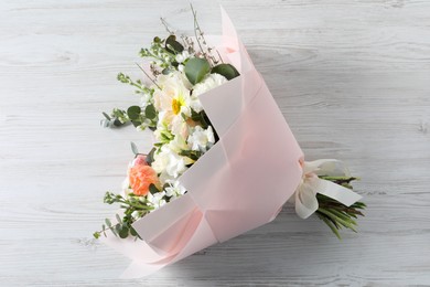 Photo of Bouquet of beautiful flowers on white wooden table, top view