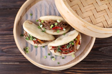 Photo of Delicious gua bao (pork belly buns) in bamboo steamer on wooden table, top view