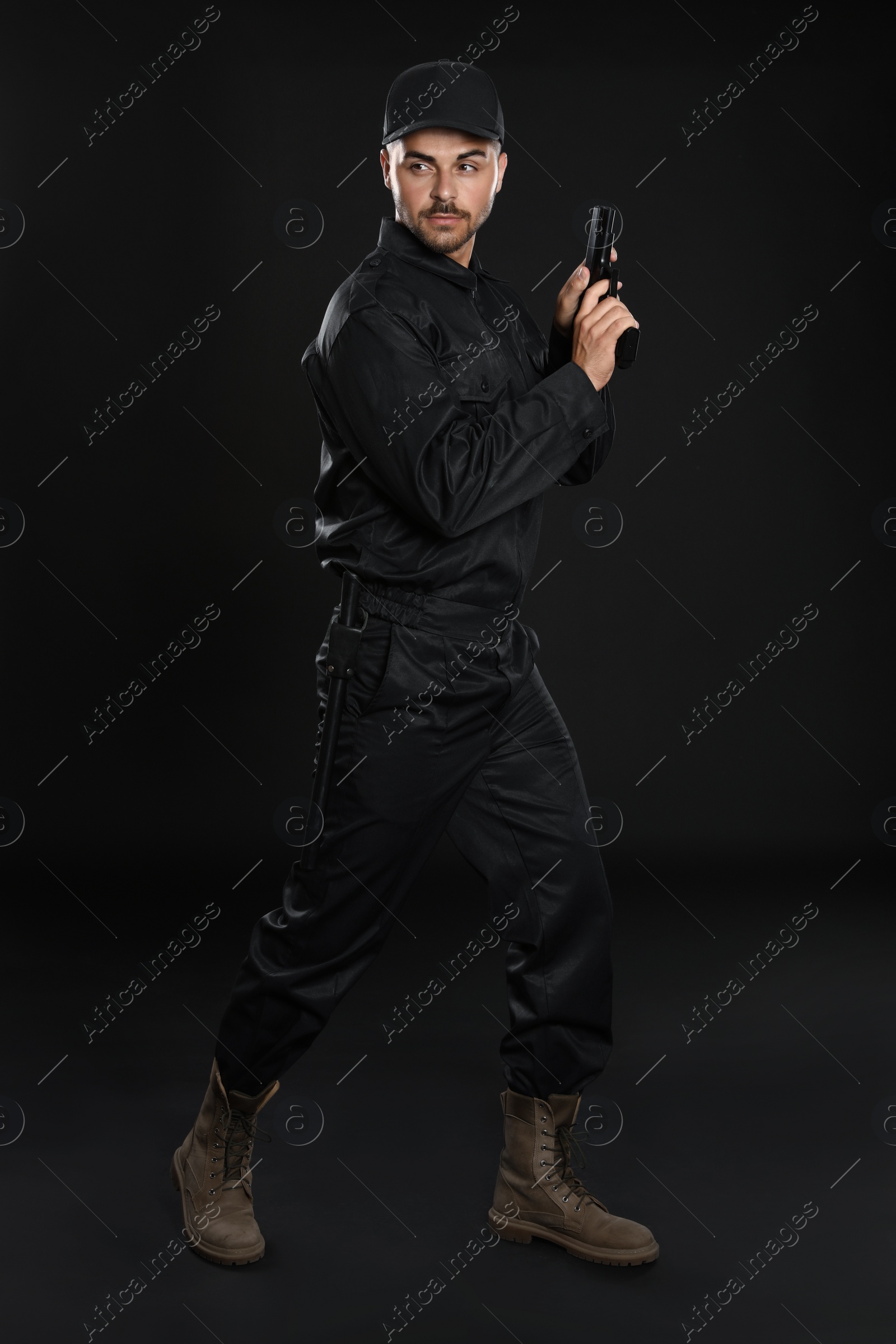 Photo of Male security guard in uniform with gun on dark background