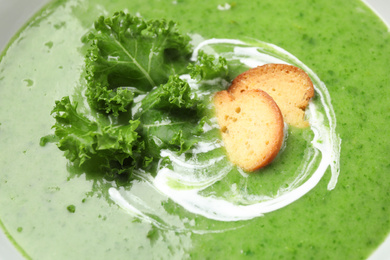Photo of Tasty kale soup with crispy croutons, closeup