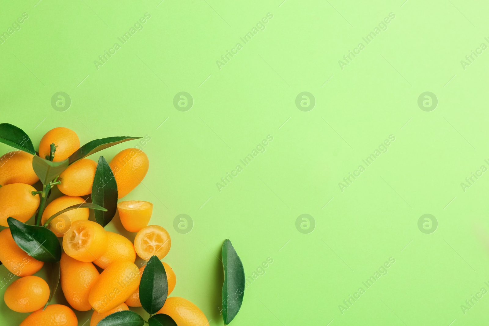 Photo of Fresh ripe kumquats on light green background, flat lay. Space for text