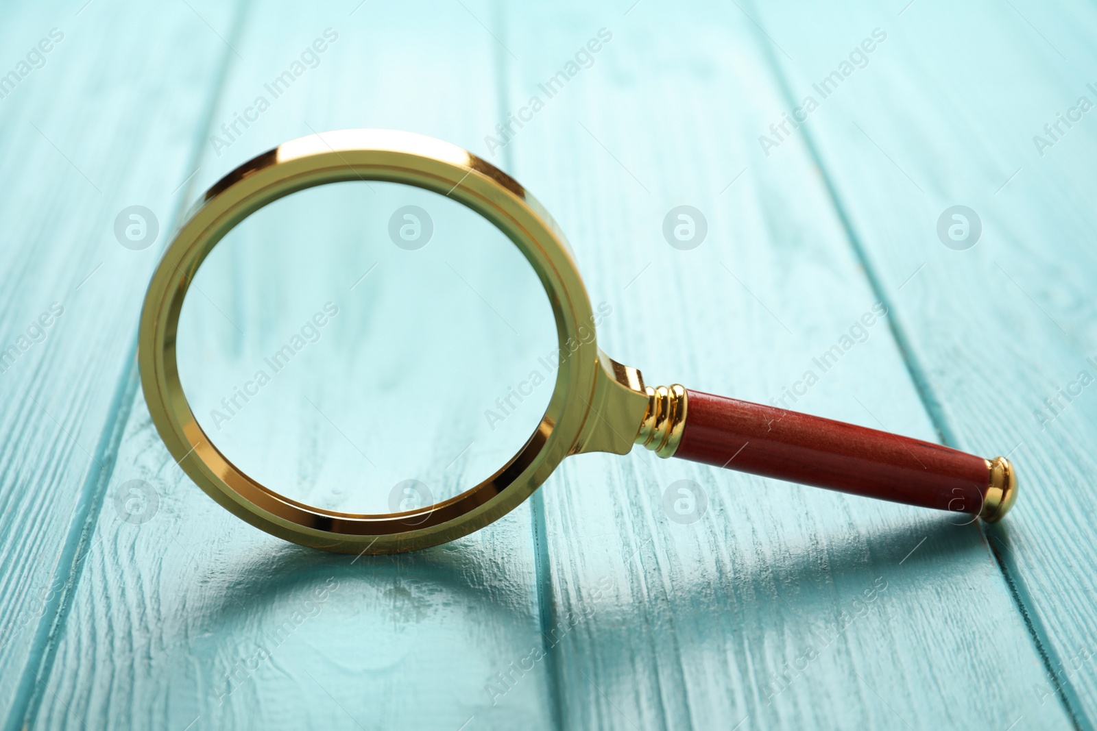 Photo of Magnifier glass on light blue wooden background, closeup. Find keywords concept