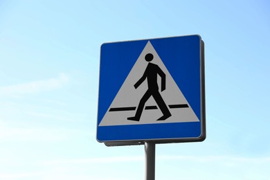 Photo of Pedestrian crossing road sign against blue sky