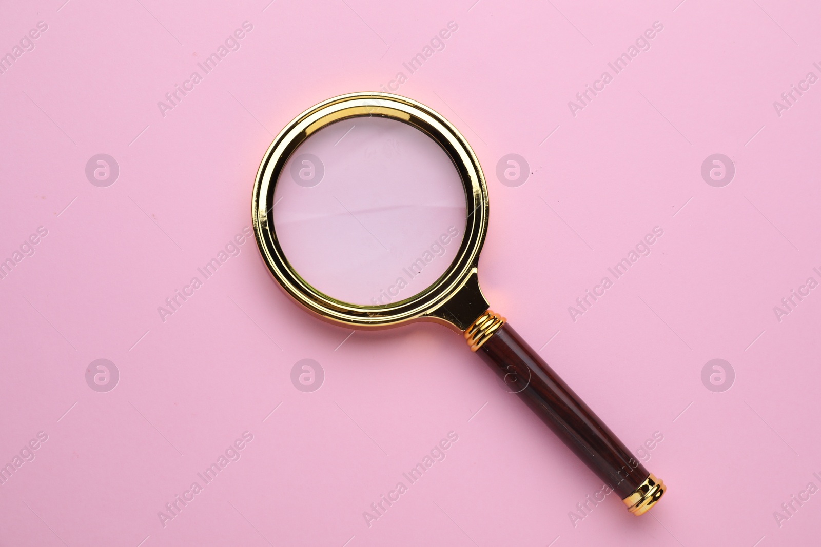 Photo of Magnifying glass on pink background, top view