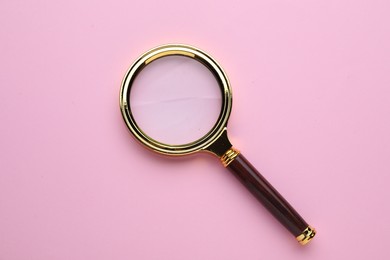 Photo of Magnifying glass on pink background, top view
