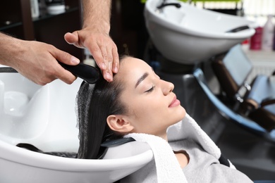 Stylist washing client's hair at sink in beauty salon