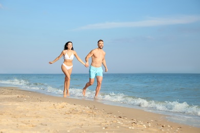 Photo of Happy young couple running together on beach