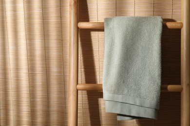 Green terry towel on wooden ladder indoors, space for text