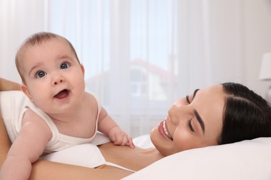 Young mother with her little baby on bed at home