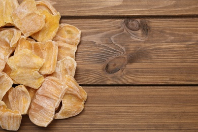 Photo of Delicious dried jackfruit slices on wooden table, flat lay. Space for text