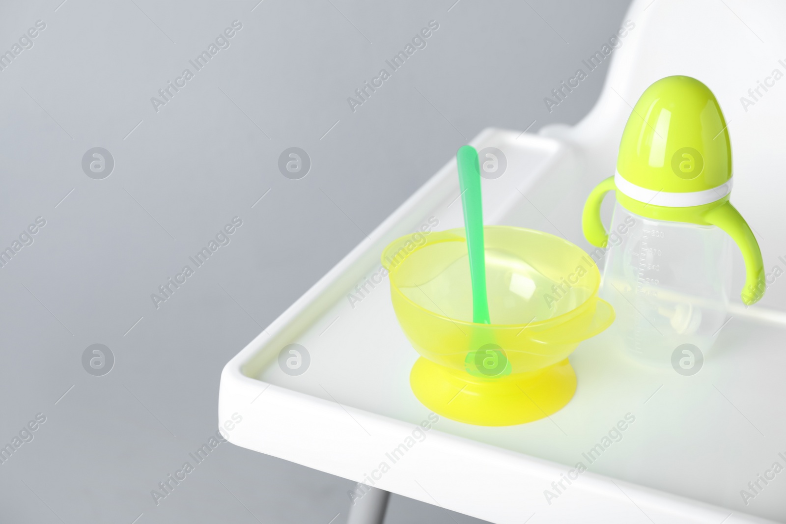 Photo of Set of plastic dishware on white feeding table. Serving baby food