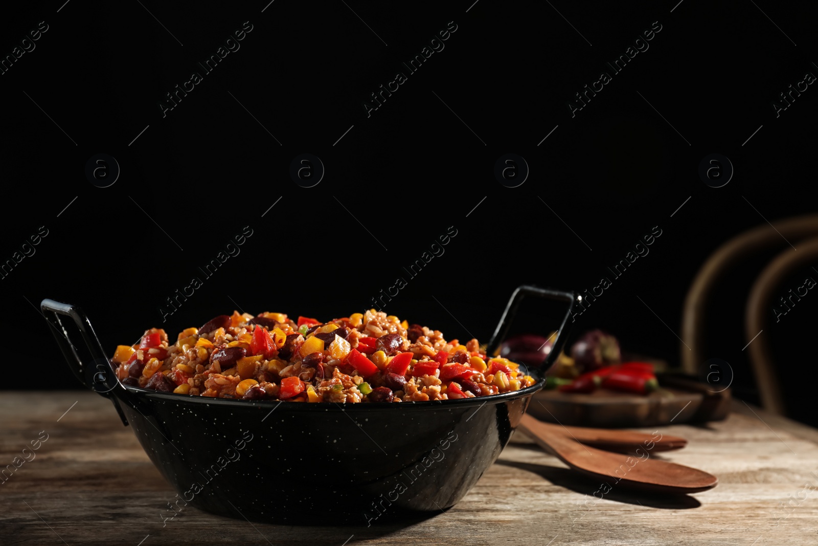 Photo of Pan with tasty chili con carne on wooden table. Space for text