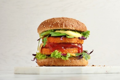 Photo of Vegan burger with carrot patties served on table against light background