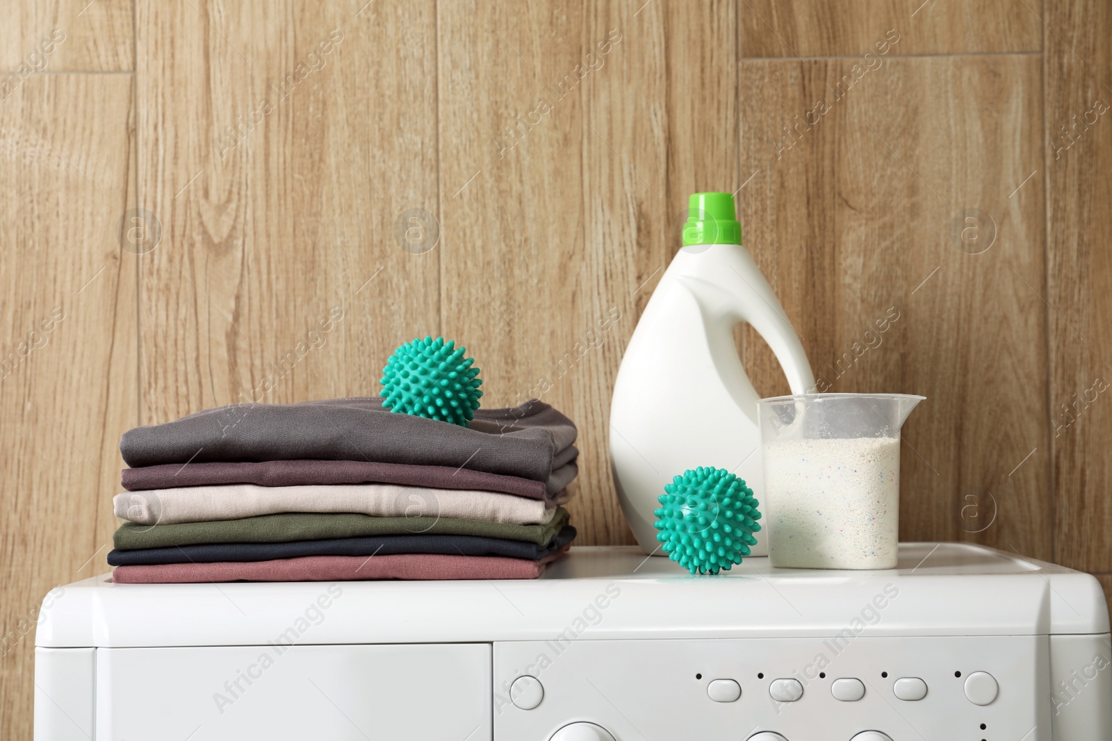 Photo of Dryer balls, stacked clean clothes and detergents on washing machine