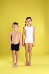 Photo of Cute little children in underwear on yellow background