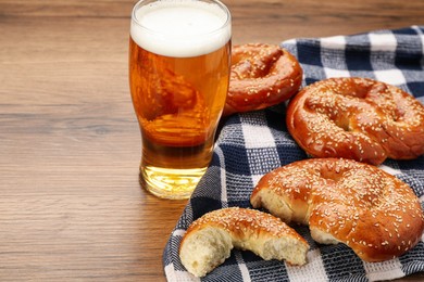Photo of Tasty pretzels and glass of beer on wooden table