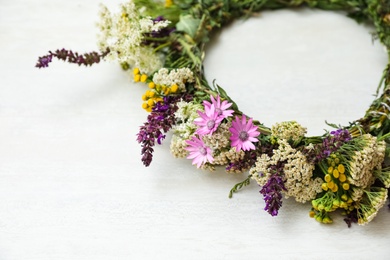 Photo of Beautiful wreath made of wildflowers on white table, closeup