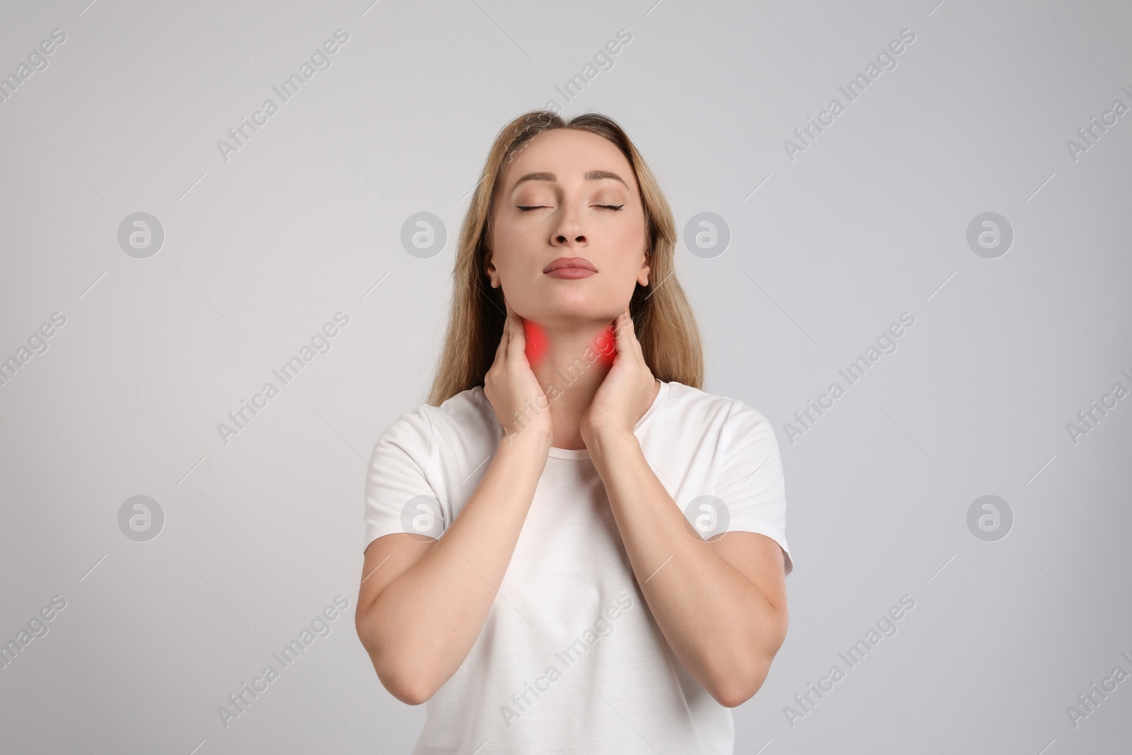 Image of Young woman doing thyroid self examination on light grey background
