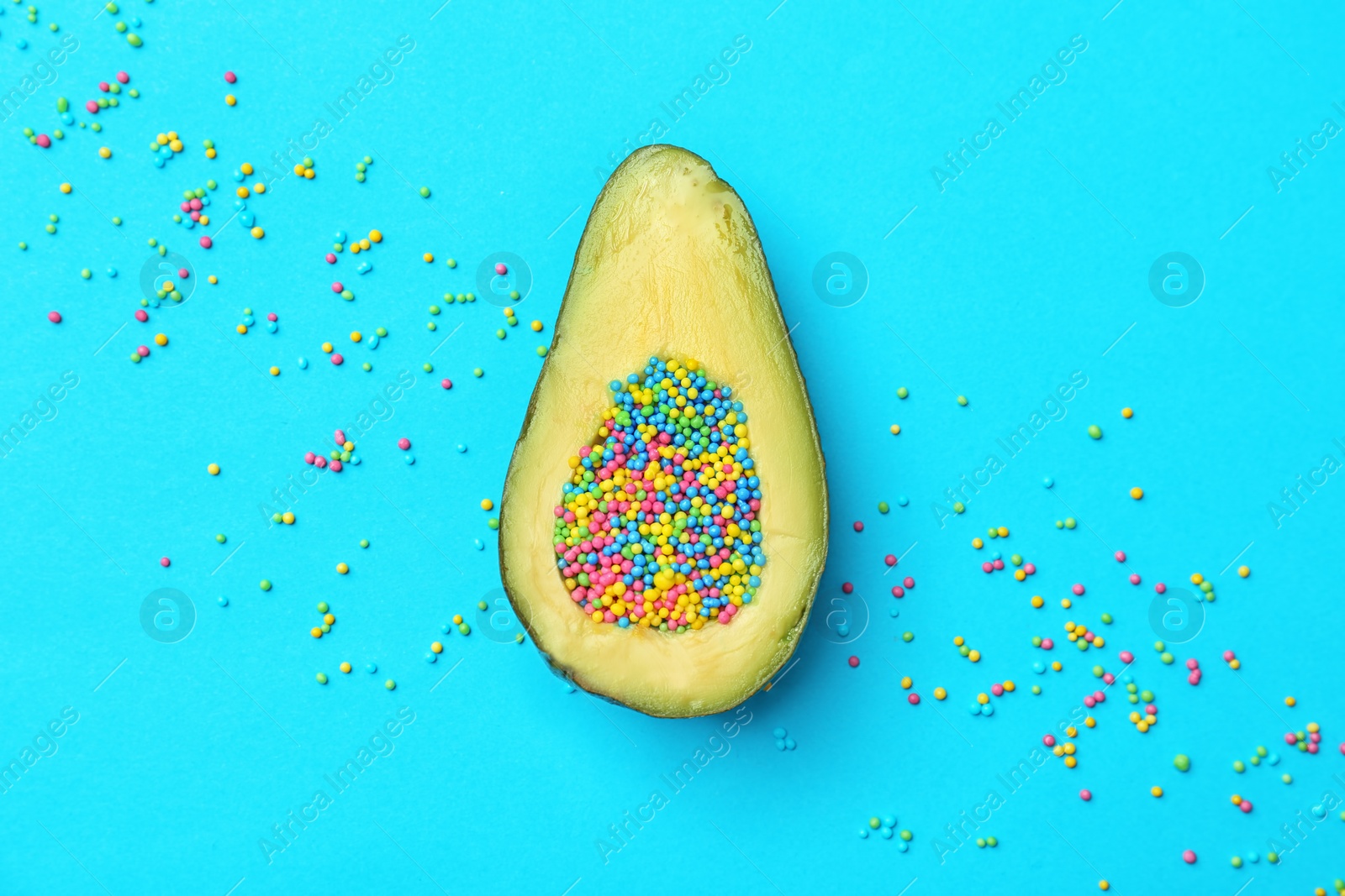 Photo of Composition with ripe avocado and sprinkles on color background, top view