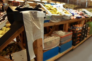 Plastic bags near rack with fruits in supermarket, space for text
